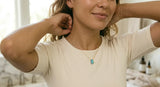 Woman unclasping opal necklace at bathroom sink
