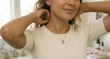Woman unclasping opal necklace at bathroom sink